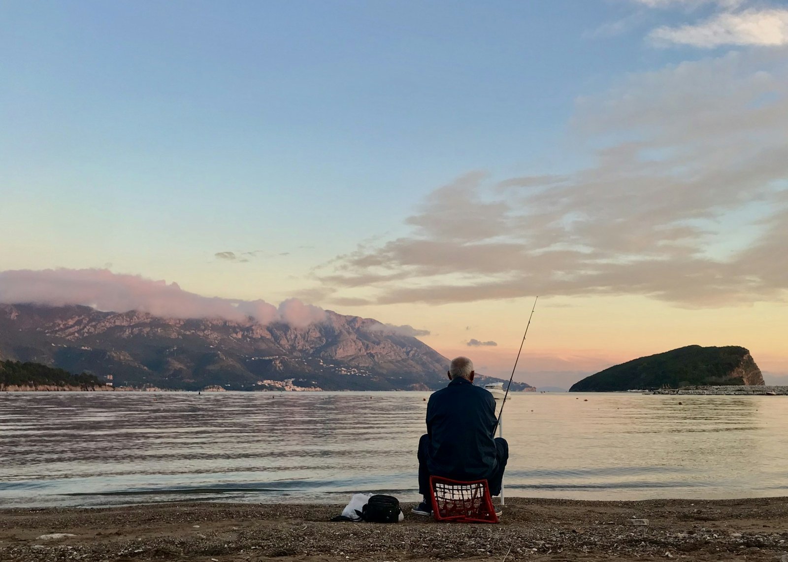 Person fishing on a quiet shore at sunset
