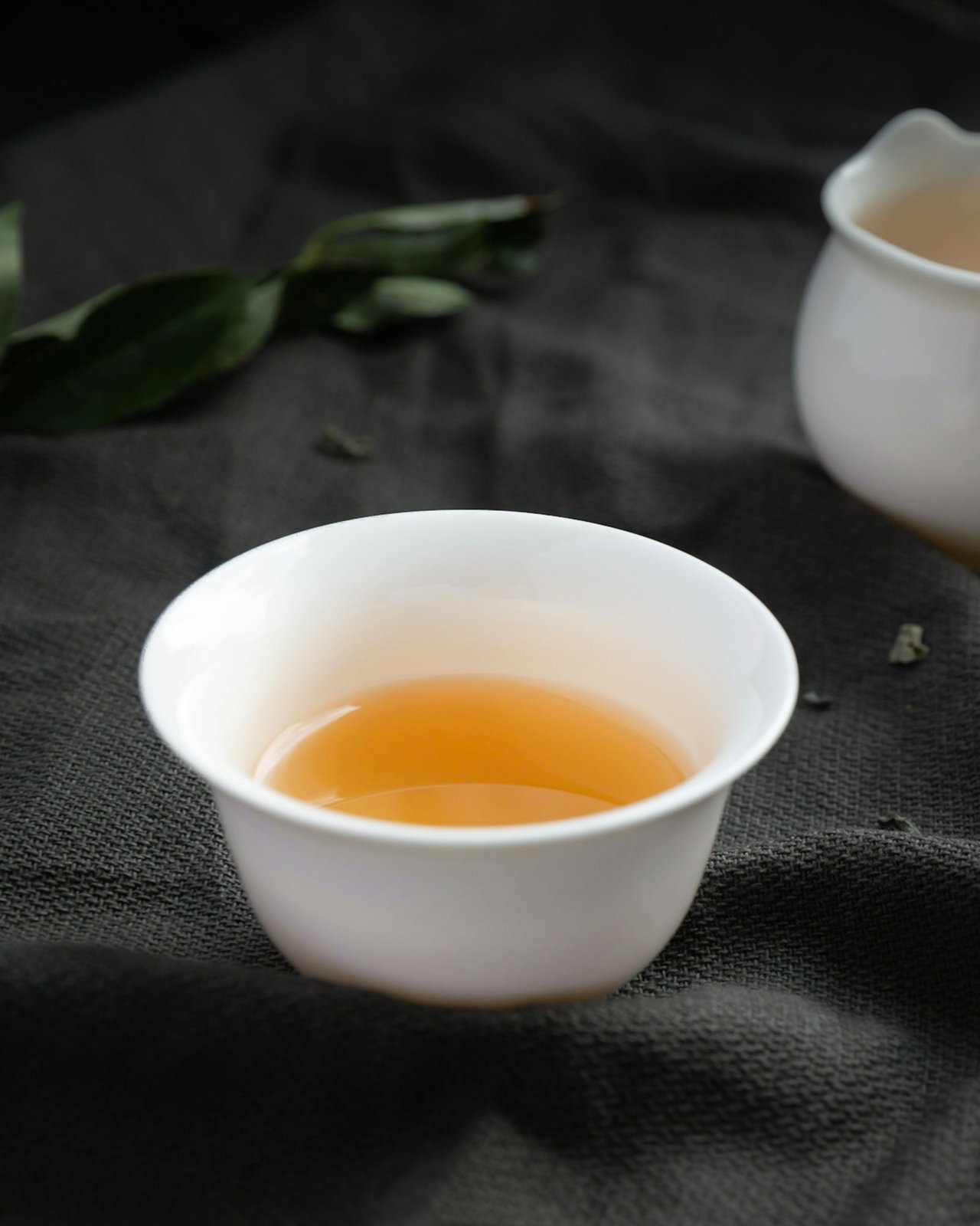 Small white porcelain tea cup filled with golden tea