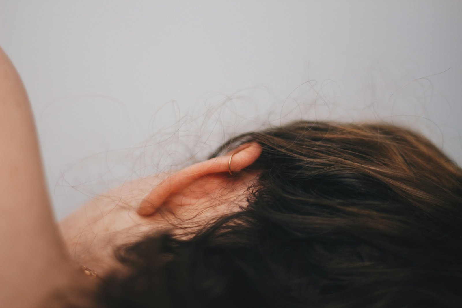 Close-up of an ear framed by brown hair