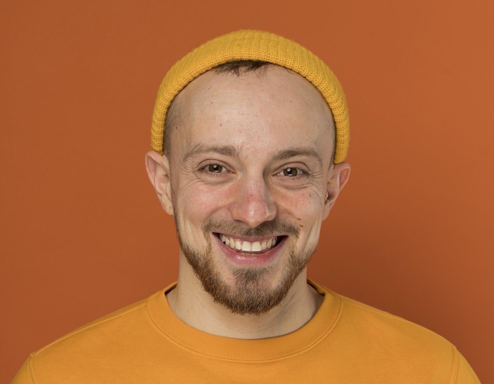 Smiling young man in a yellow beanie with ears that stand out from his head