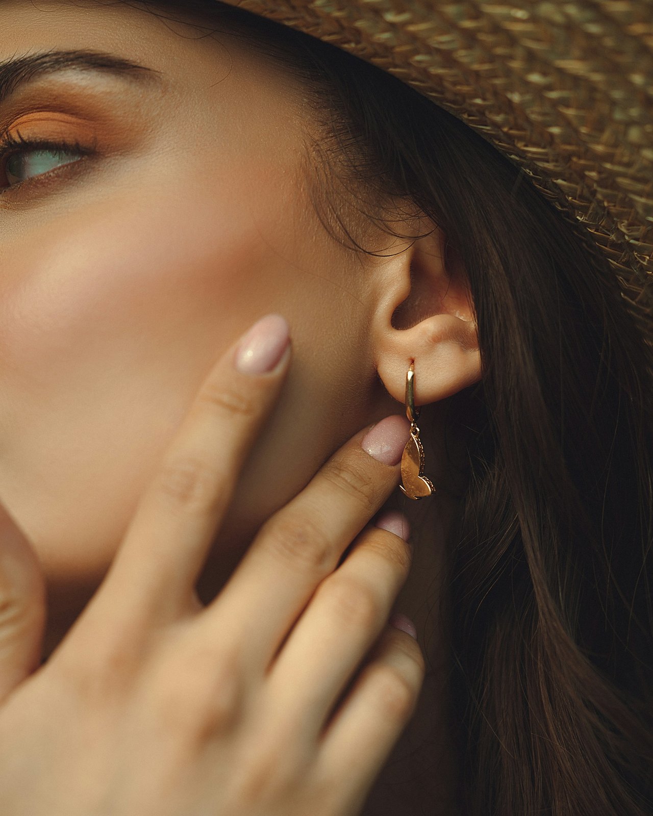 Woman's fingers touching the skin beside her earlobe