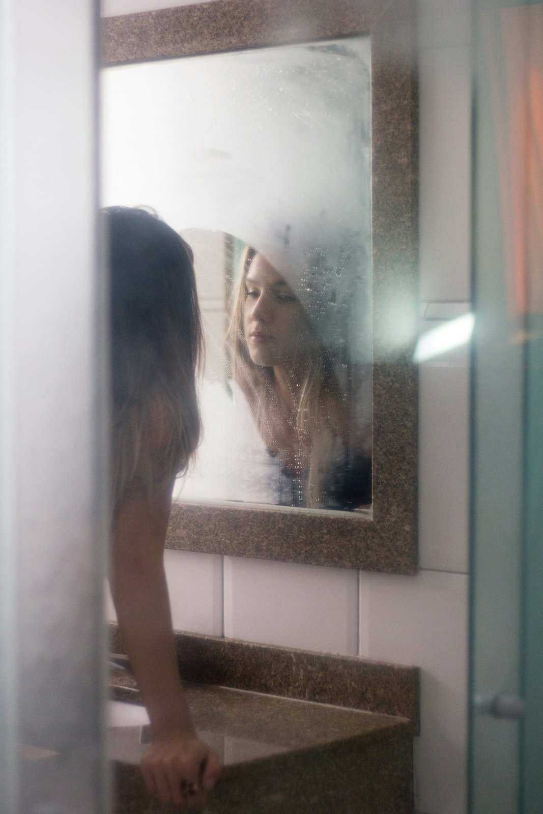 Woman looking at herself in a bathroom mirror