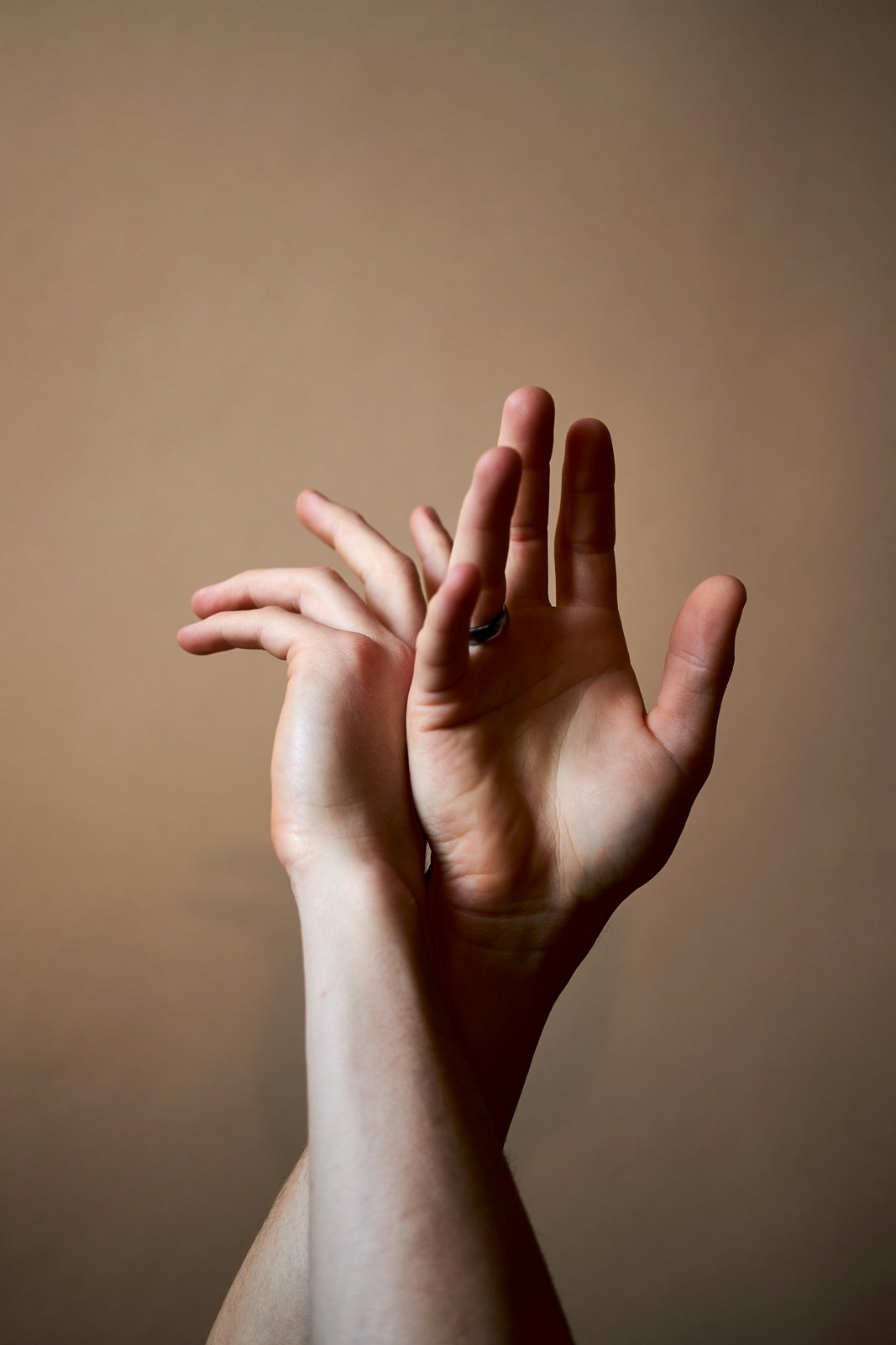 Slender hand with long fingers against a brown wall