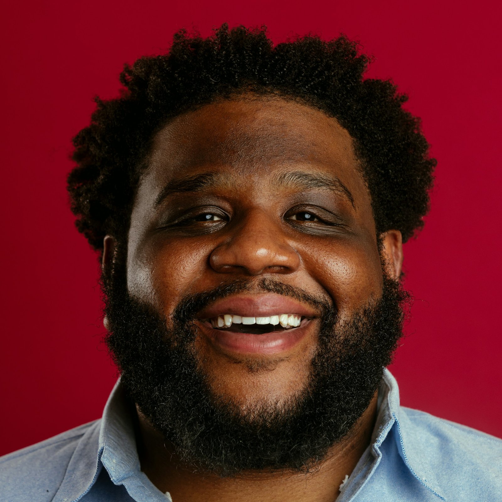 Smiling man with a full, round face and a thick beard