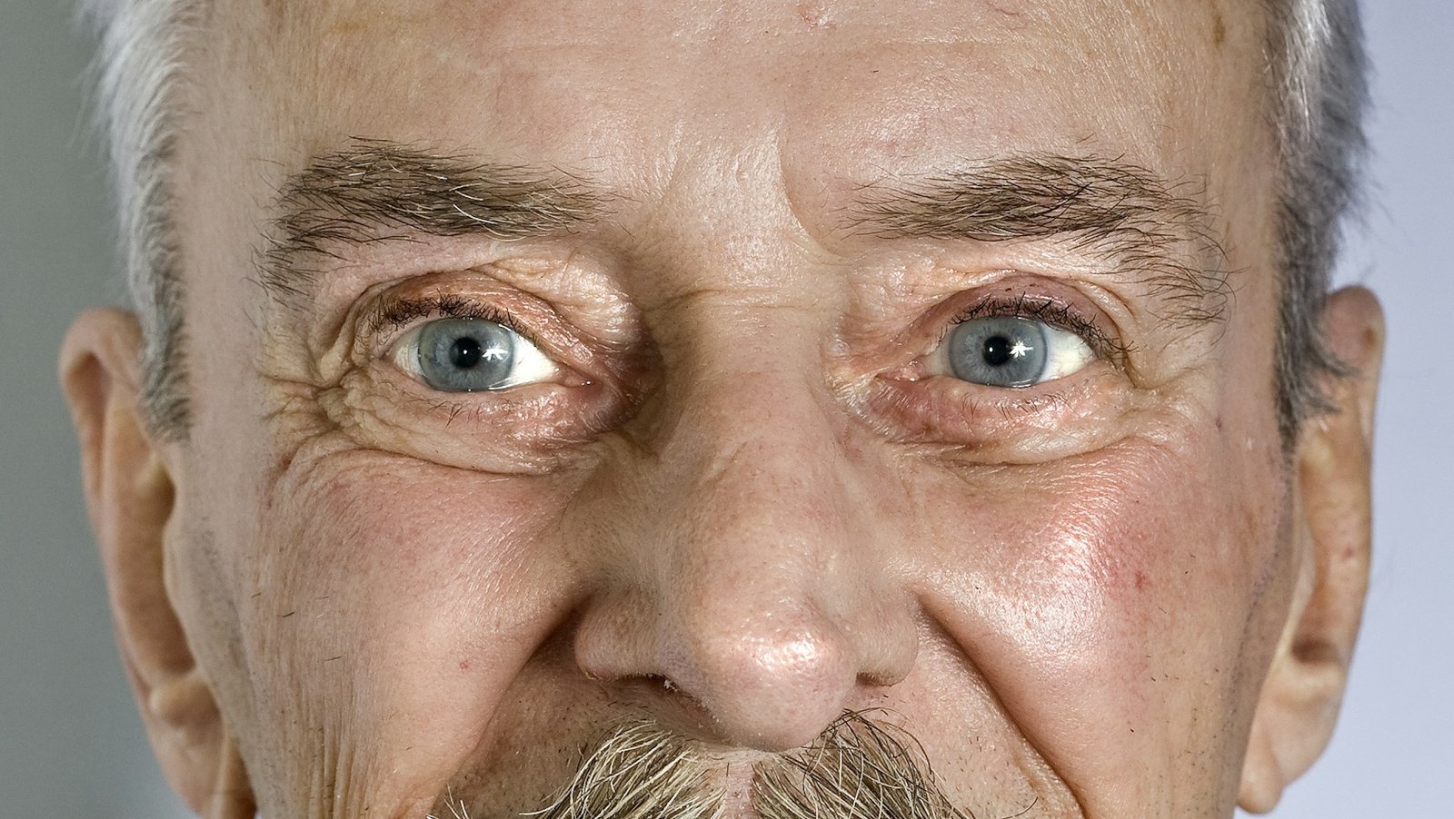 Smiling older man with soft brows and fine wrinkles around his eyes