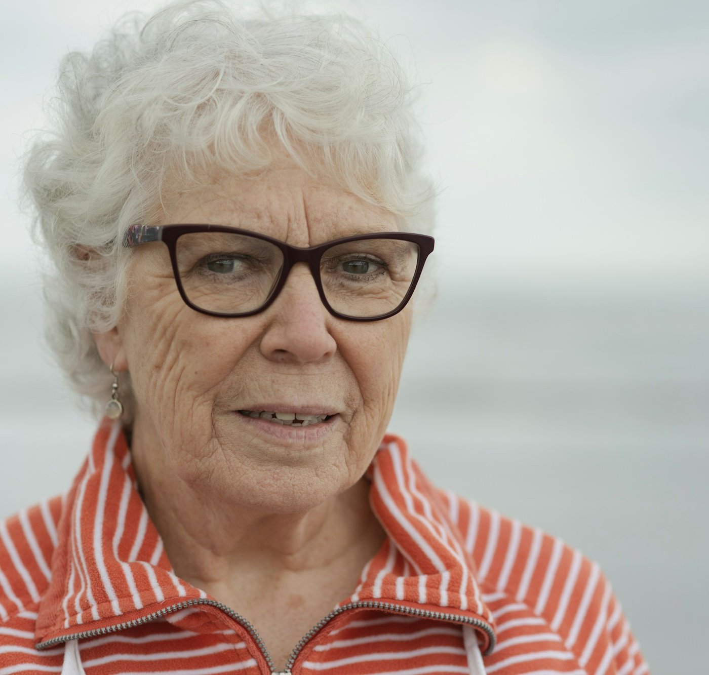 Elderly woman smiling gently, with a rounded chin
