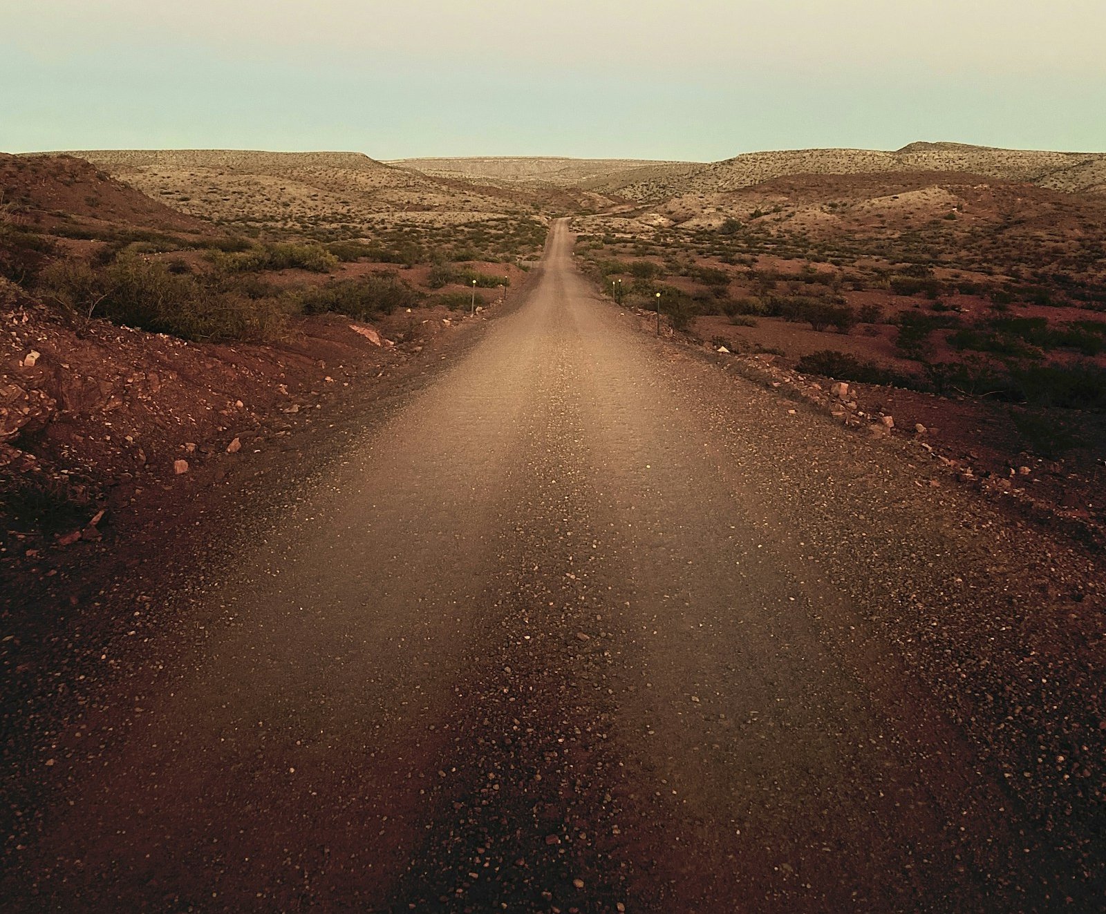 Gravel road stretching ahead through open hills