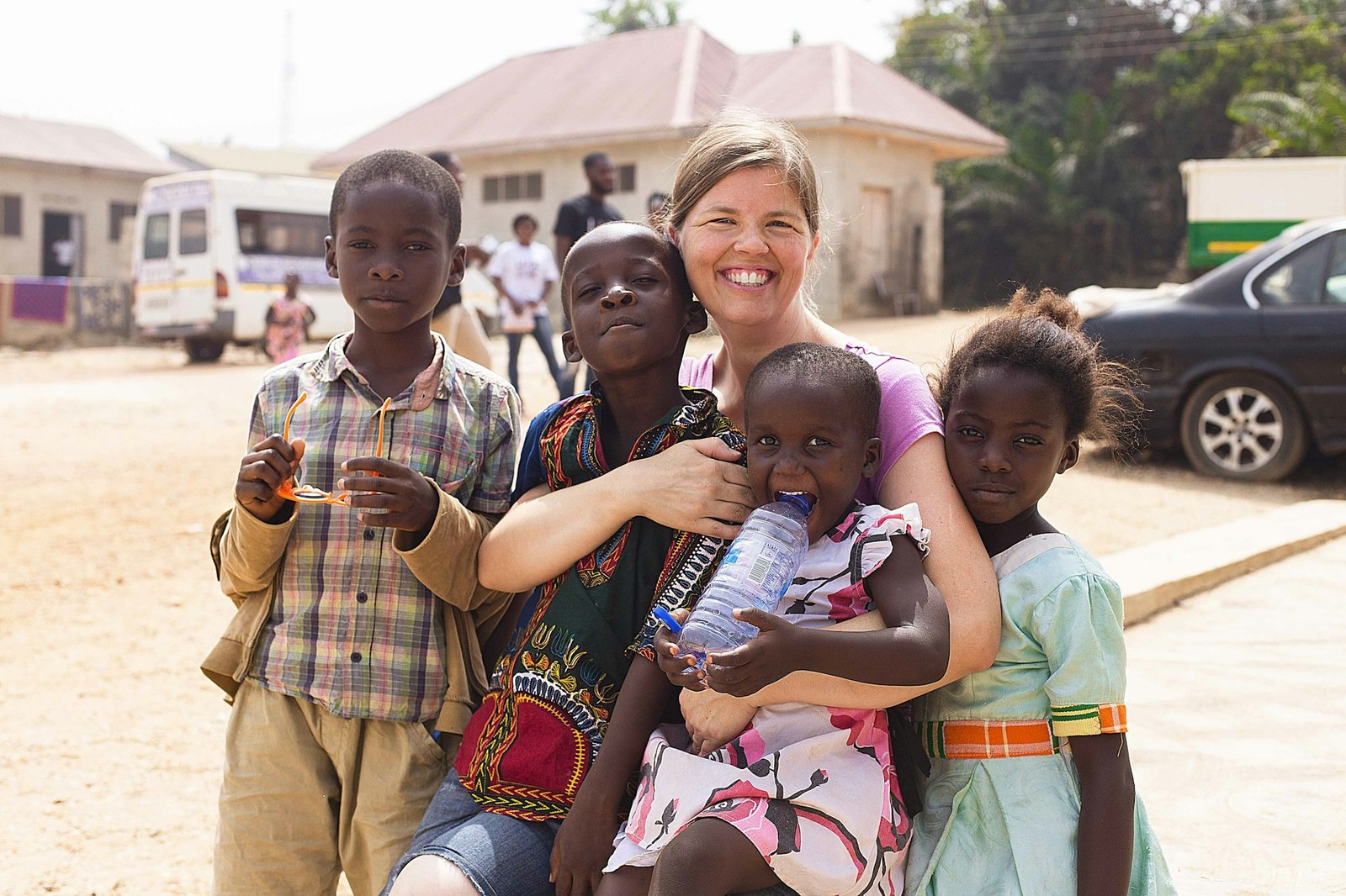 Smiling volunteer holding a child among a group of children
