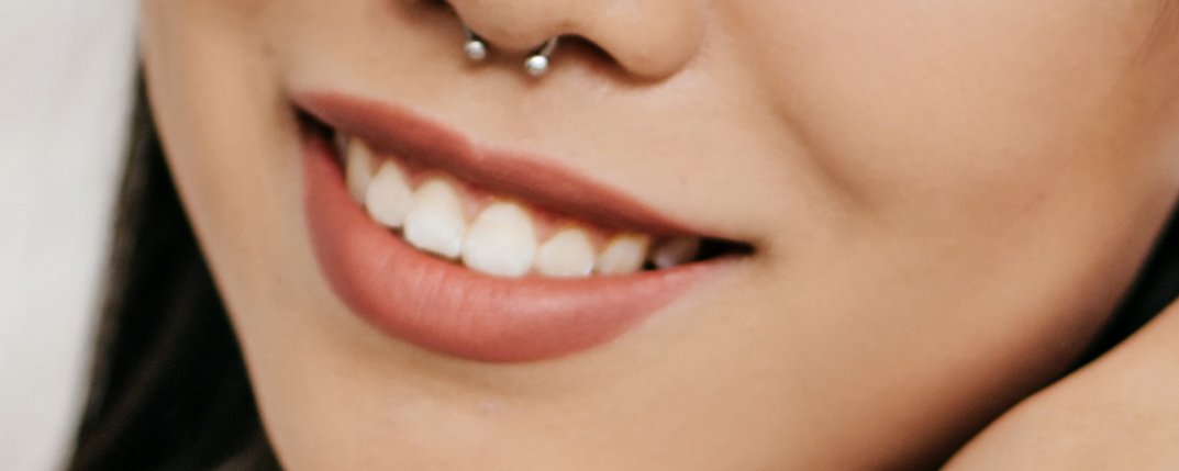 Close-up of full rosy lips smiling with upturned corners and straight teeth