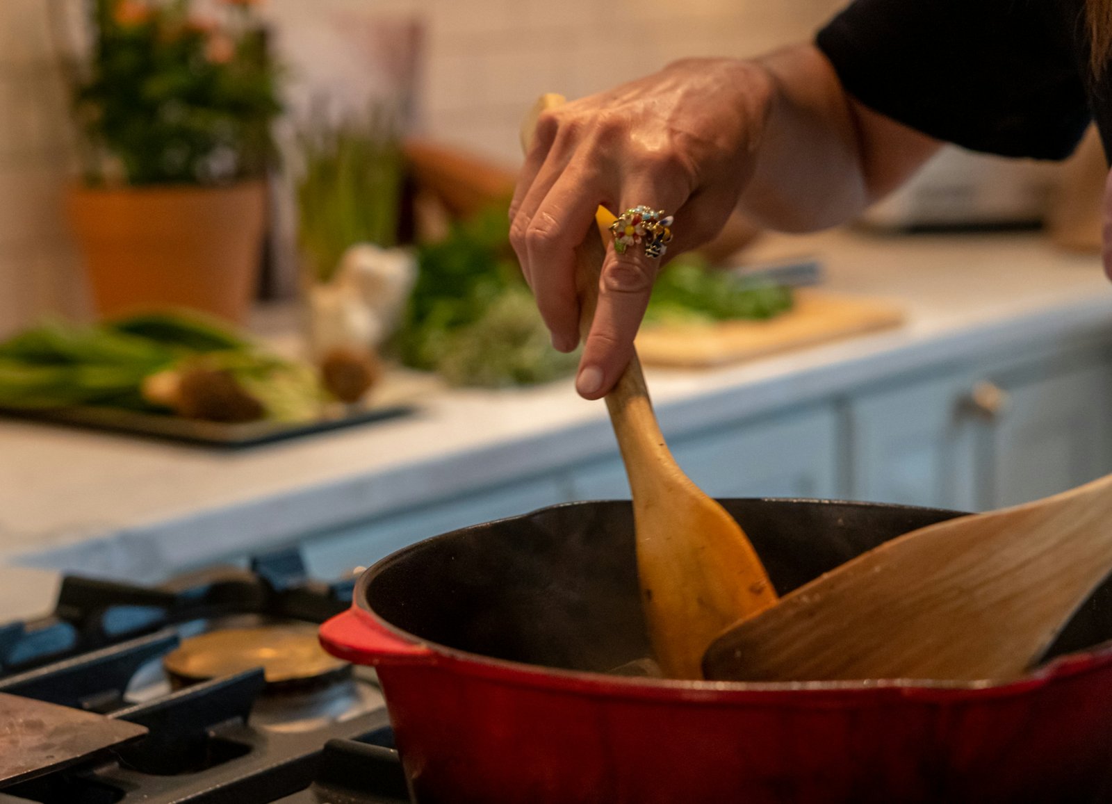 A hand stirring a pot with a wooden spoon