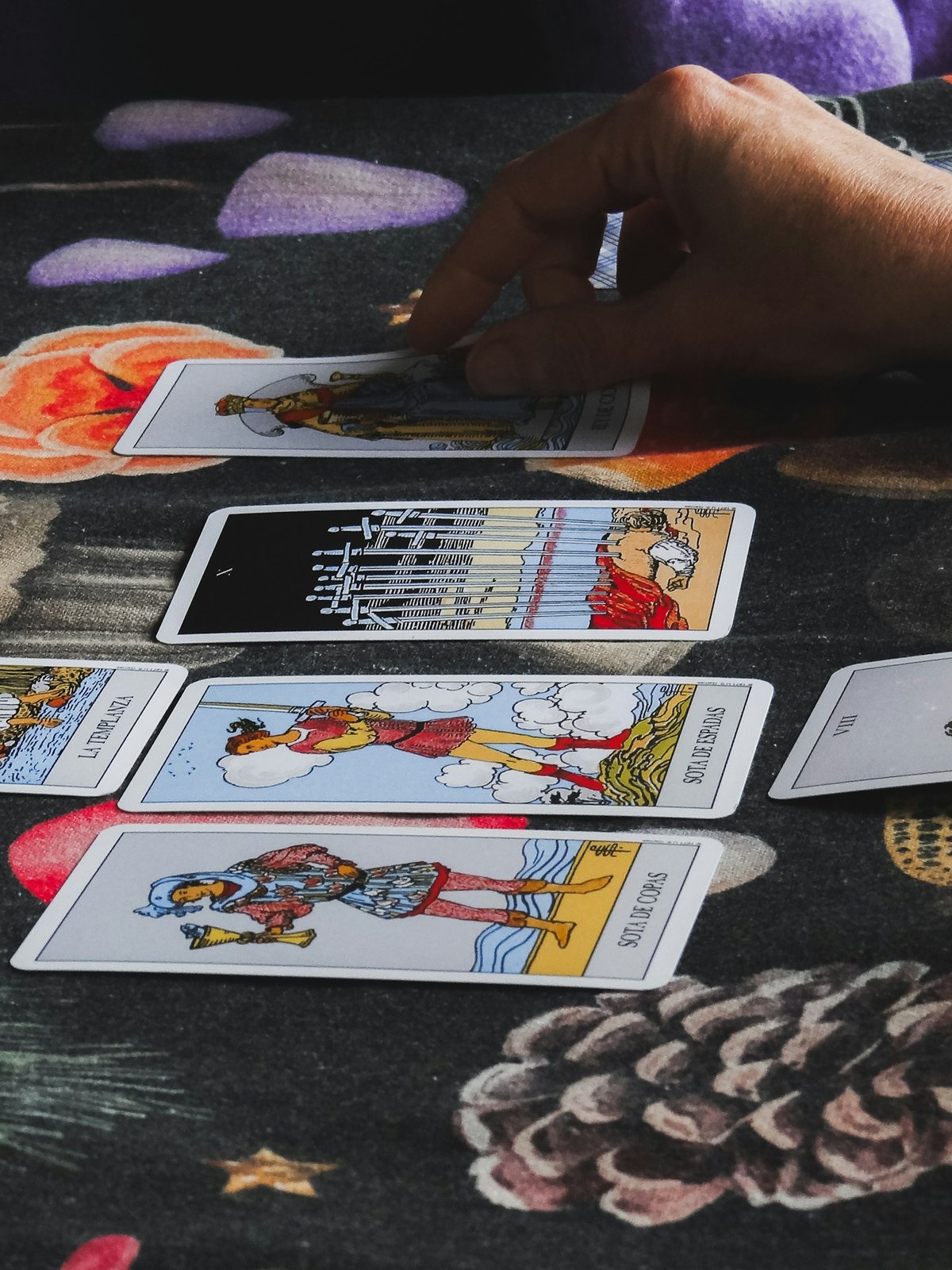 Hand laying tarot cards out on a table during a reading