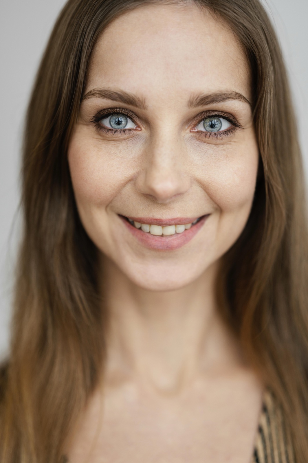 Smiling young woman with large eyes and a soft, rounded face