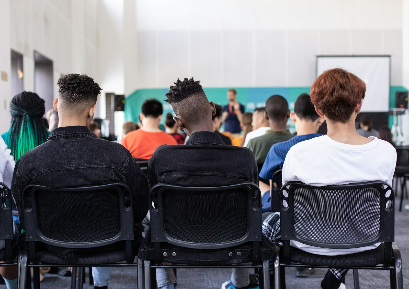 Young people seated in rows in a lecture room, seen from behind