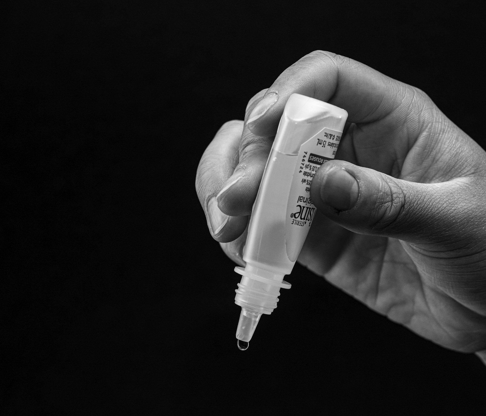 Hand holding a bottle of eye drops